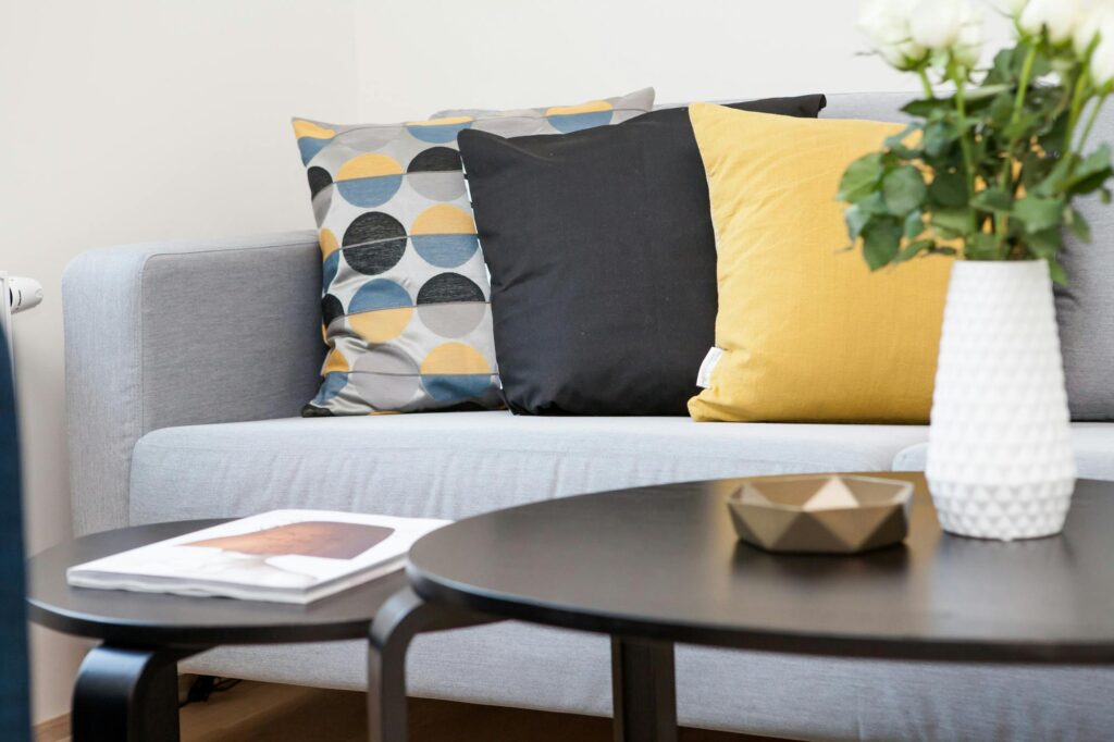 pexels-photo-298842-298842 Contemporary living room interior featuring a stylish sofa, decorative pillows, and a vase of flowers.